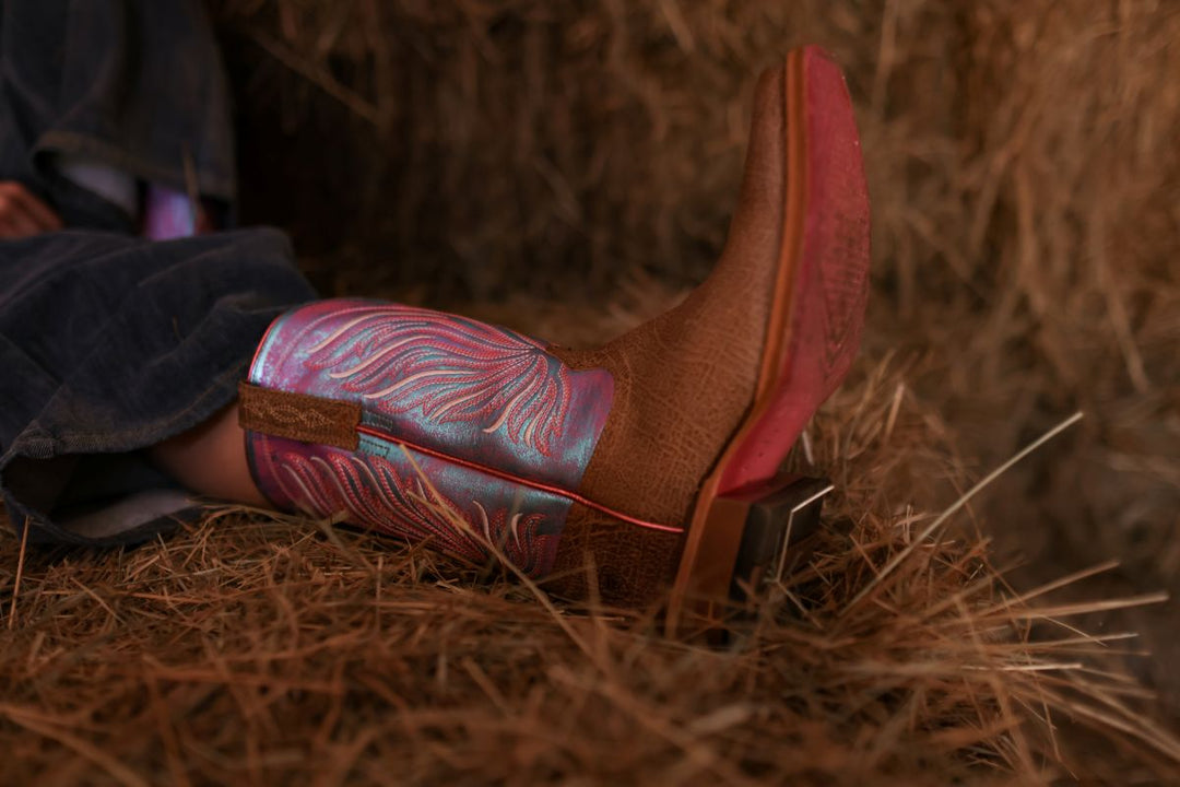ariat leather square toe cowboy boot in a barn with hay for horses