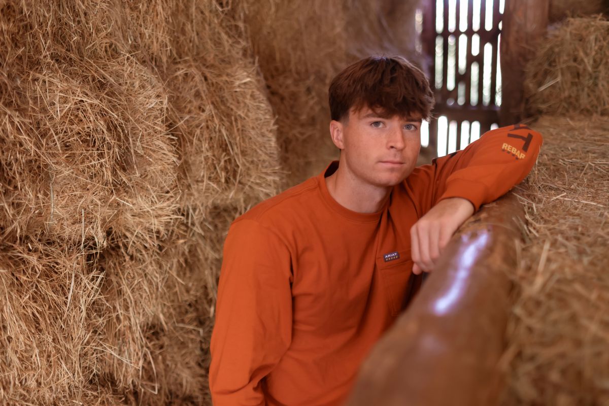 ariat rebar long sleeve work t-shirt in a barn with a man wearing it around hay