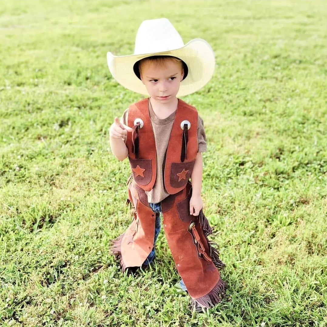 a little cowboy dressed head to toe in cowboy gear with a cowboy hat leather vest leather chaps and boots