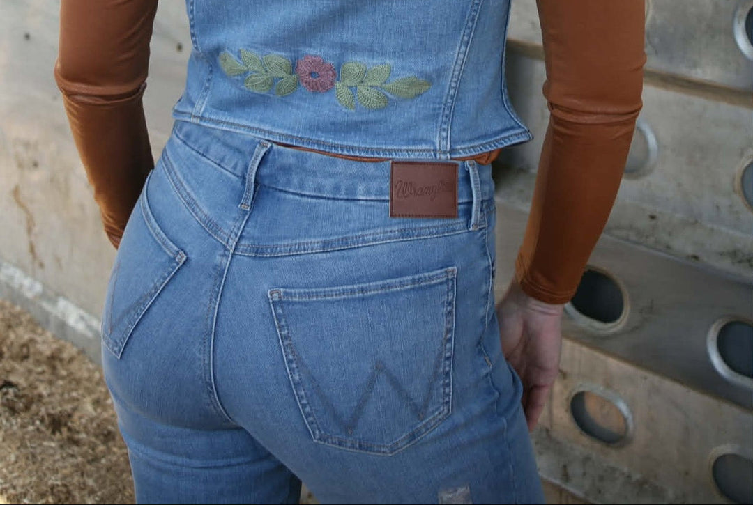 a beautiful women showing back pockets of bespoke wrangler jeans with w on back pockets