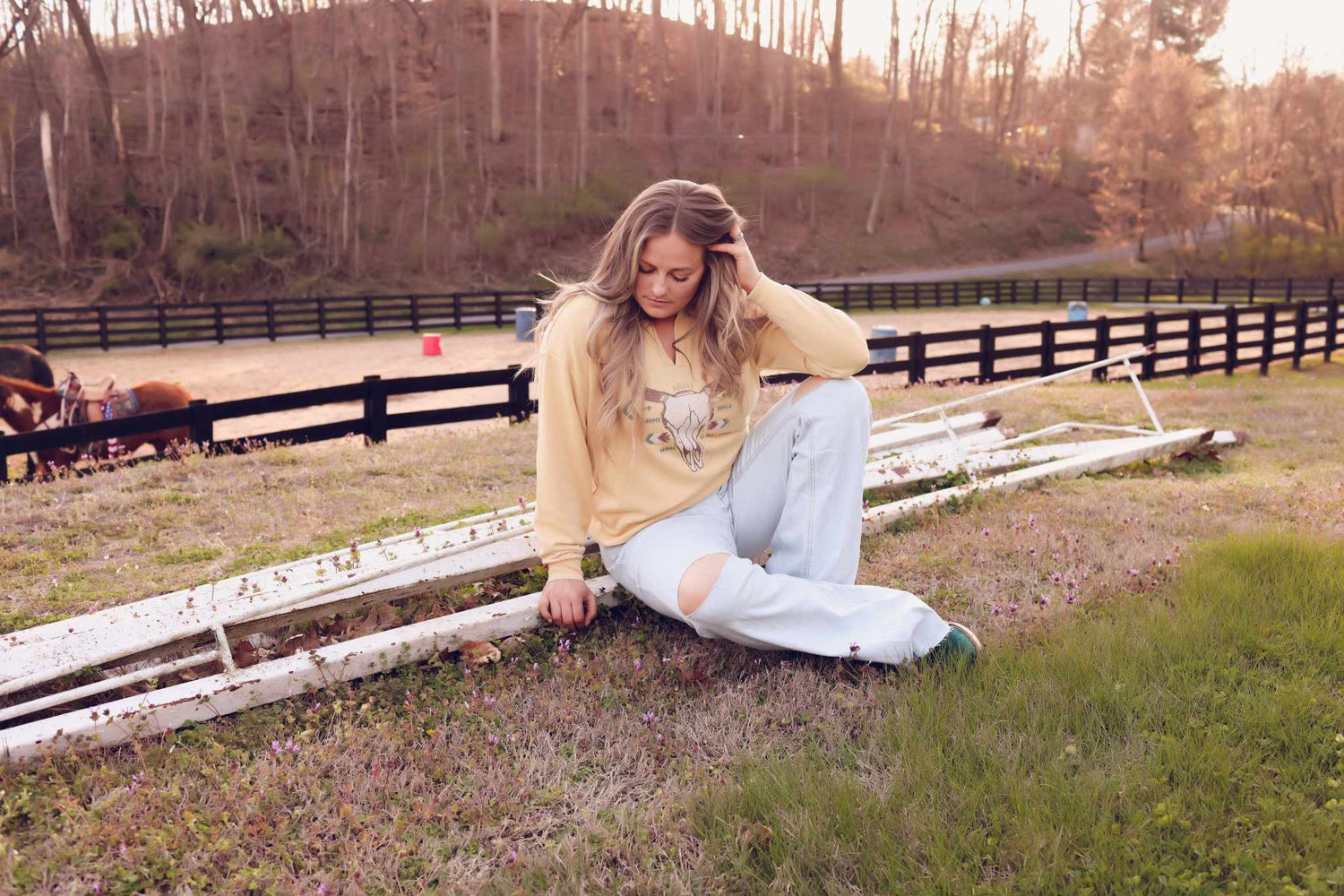 woman wearing wrangler jeans and yellow shirt sitting in field 