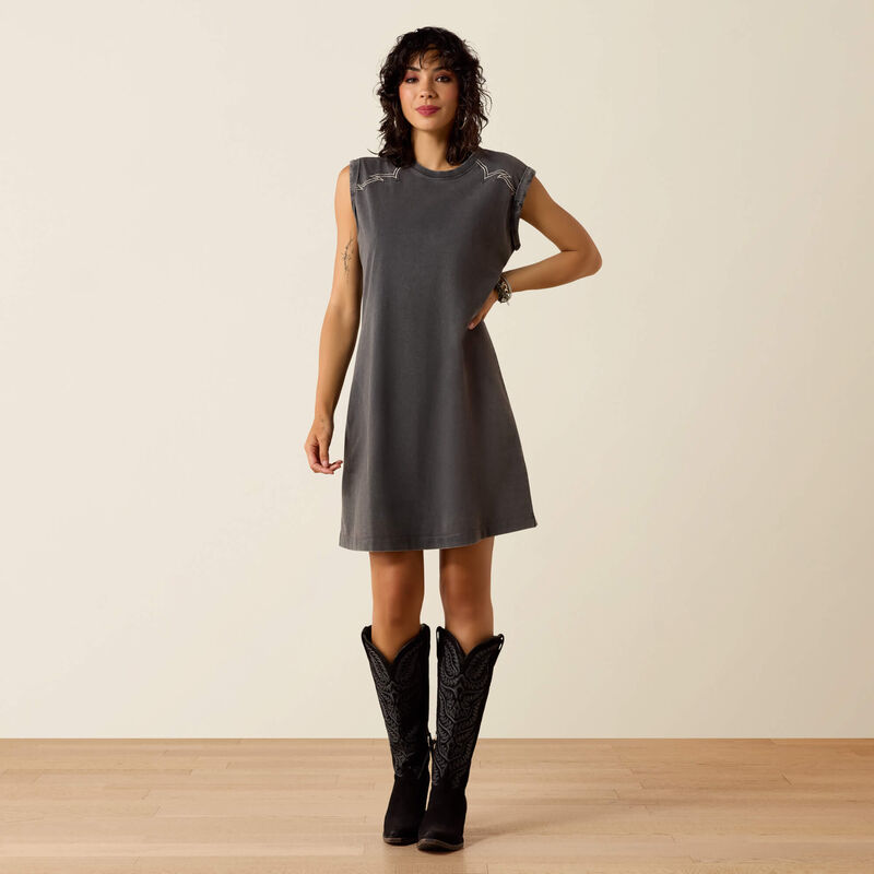 Woman wearing a gray sleeveless dress and black boots on a plain background