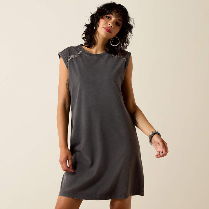 Woman wearing a gray dress with decorative sleeves against a beige background