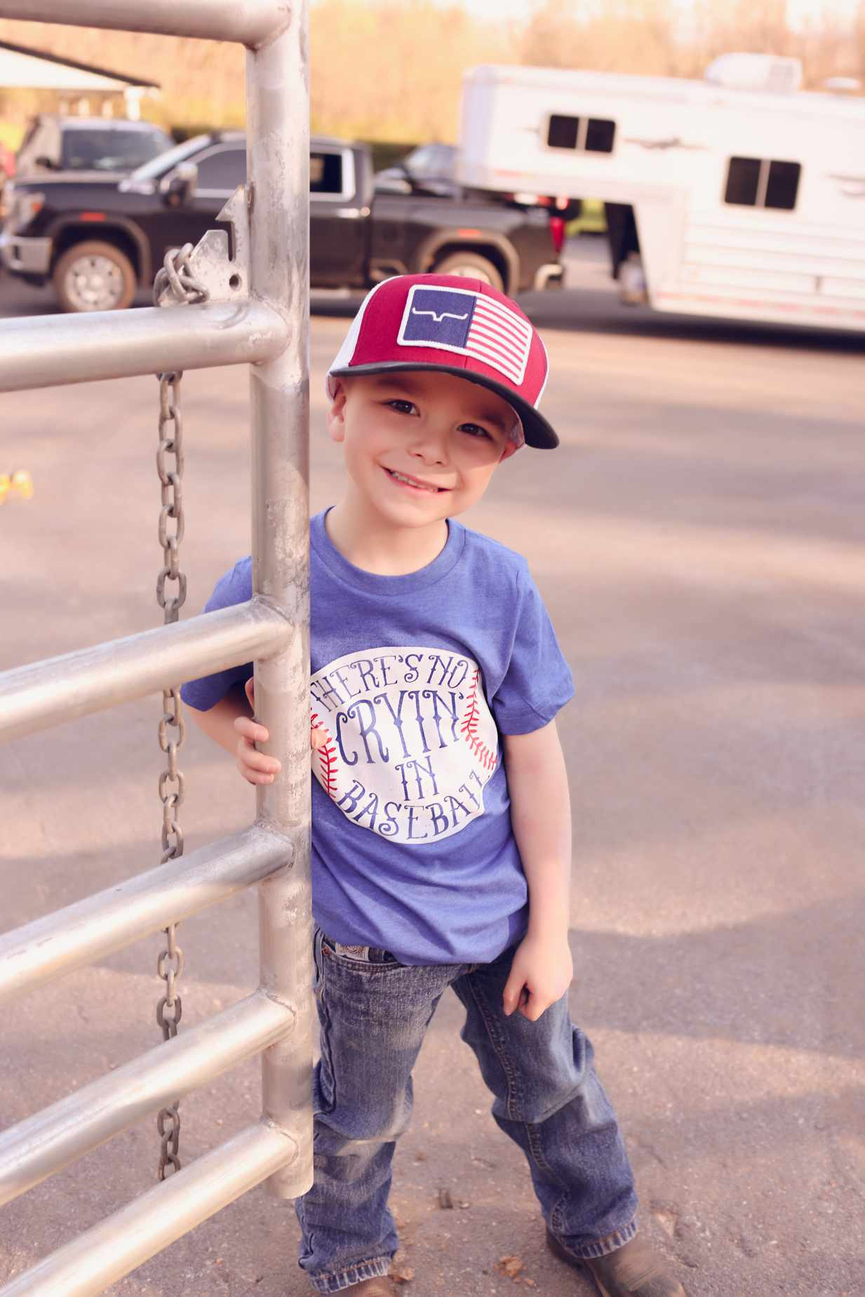 child wearing a blue shirt that says there's no crying in baseball and a red hat